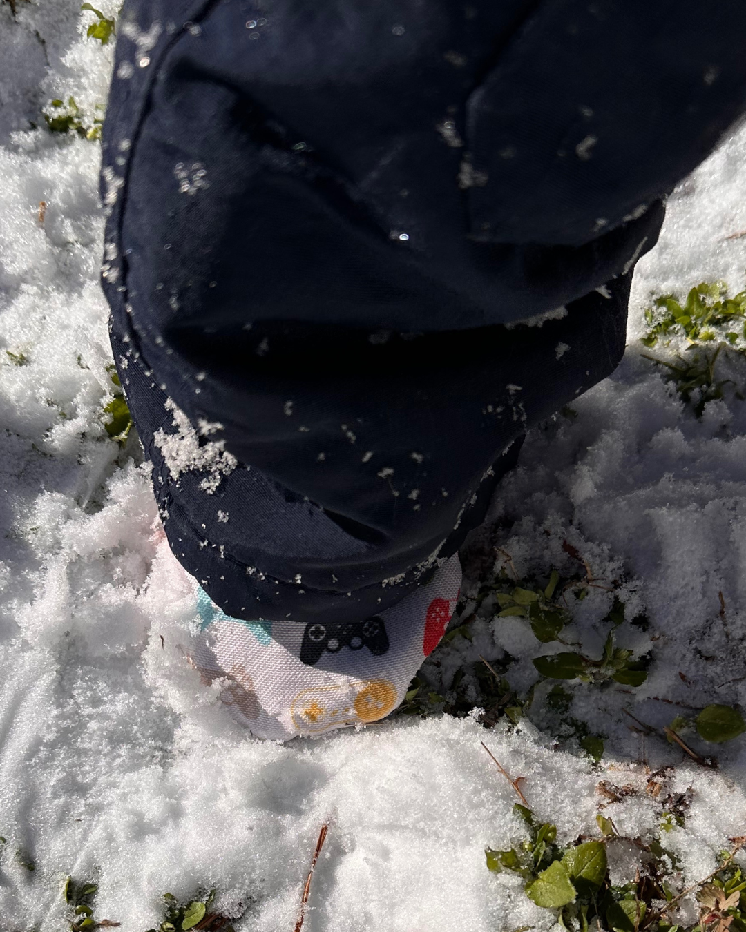 Baby wearing limited edition Game Day Cabooties eco-canvas baby shoes in the snow